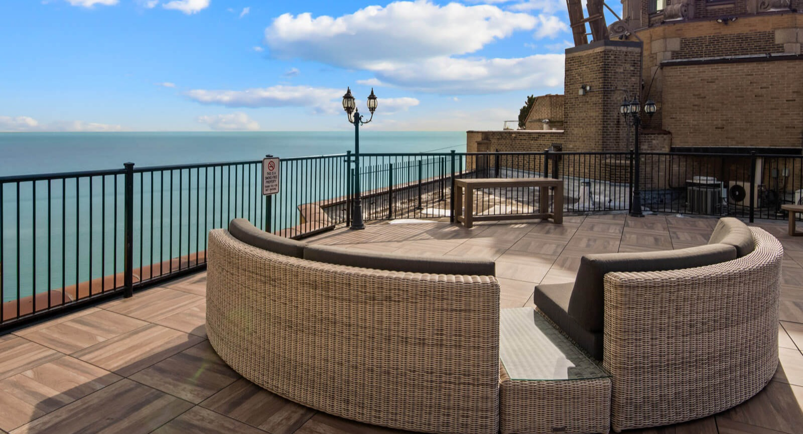 Luxurious rooftop lounge with wicker seating and breathtaking views of Lake Michigan and the Chicago skyline at The Deco North Lake Shore