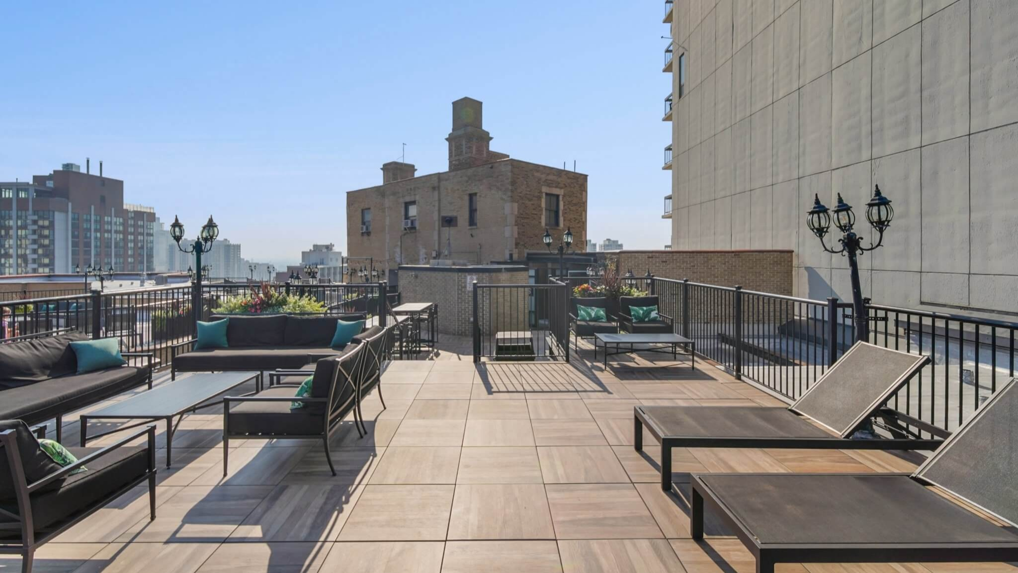 Expansive rooftop sun deck with lounge chairs, comfortable seating, and beautiful city views at The Deco North Lake Shore in Chicago
