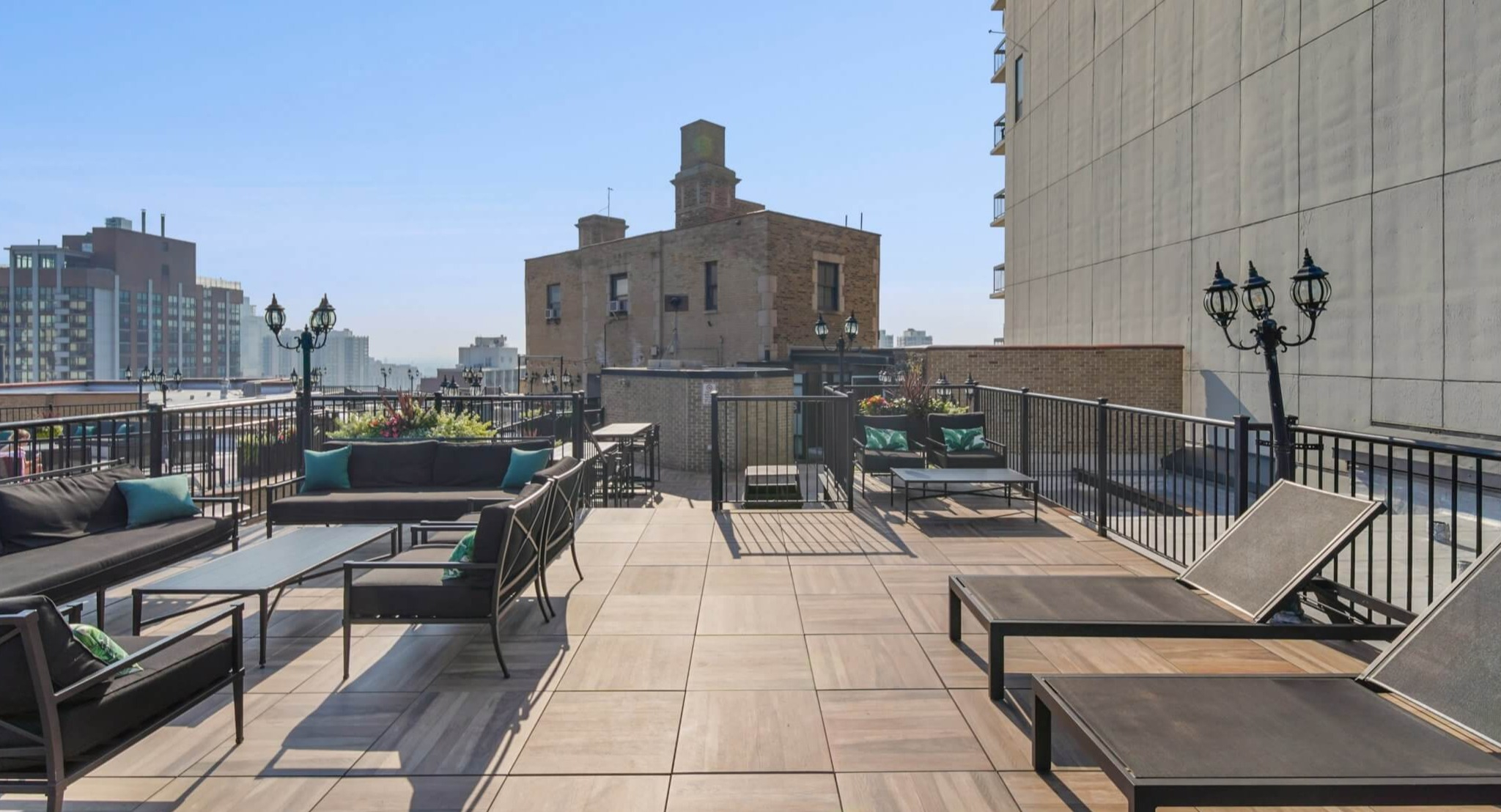 Expansive rooftop sun deck with lounge chairs, comfortable seating, and beautiful city views at The Deco North Lake Shore in Chicago
