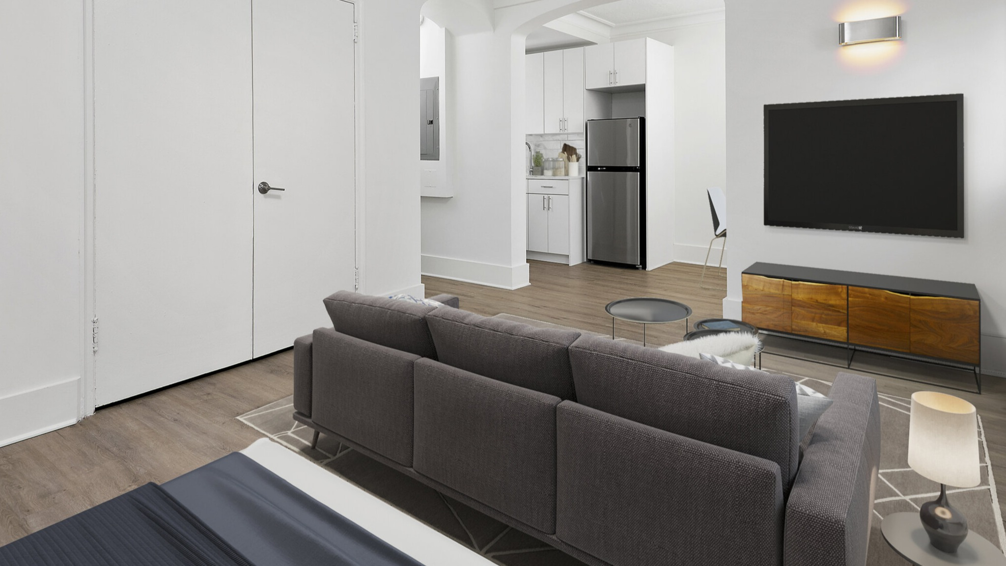 Compact studio living area featuring a comfortable sofa, modern TV unit, and an open entryway to the kitchenette at The Deco North Lake Shore in Chicago