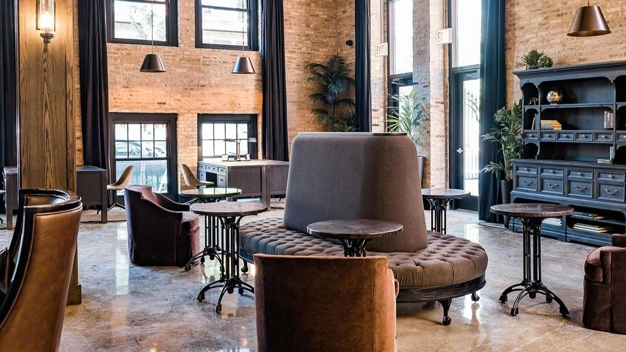 Elegant resident lounge featuring unique circular seating, individual tables, and exposed brick walls at The Duncan apartments in Chicago