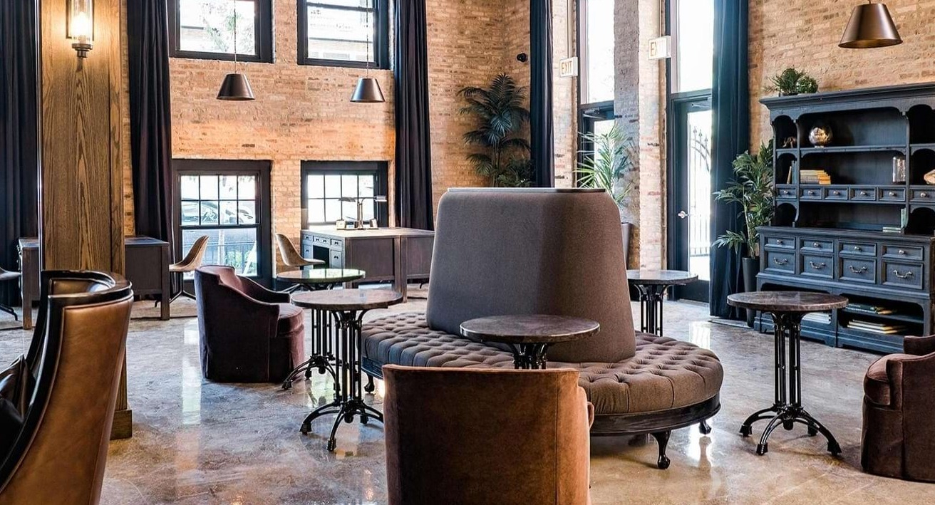 Elegant resident lounge featuring unique circular seating, individual tables, and exposed brick walls at The Duncan apartments in Chicago