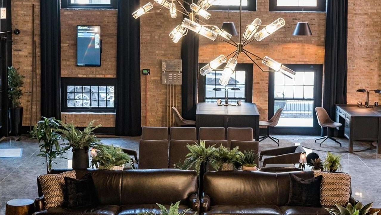 Grand lobby lounge with high ceilings, exposed brick, plush leather sofas, and modern chandeliers at The Duncan apartments in Chicago