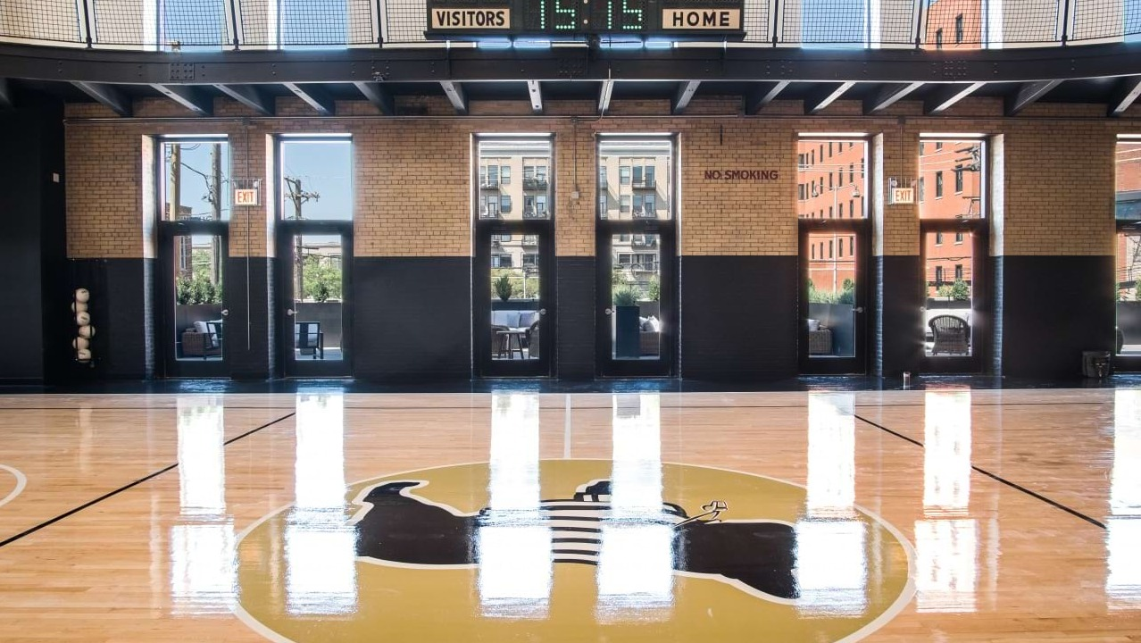 Impressive indoor basketball court with high ceilings, large windows, and a scoreboard, perfect for sports at The Duncan in Chicago