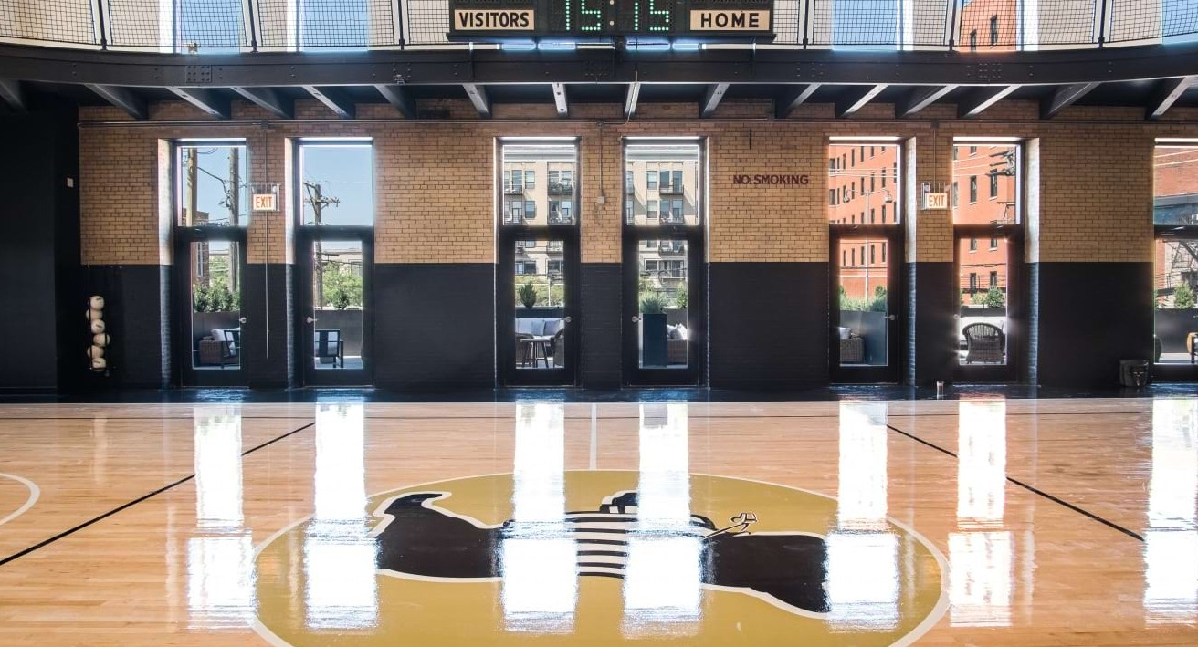 Impressive indoor basketball court with high ceilings, large windows, and a scoreboard, perfect for sports at The Duncan in Chicago