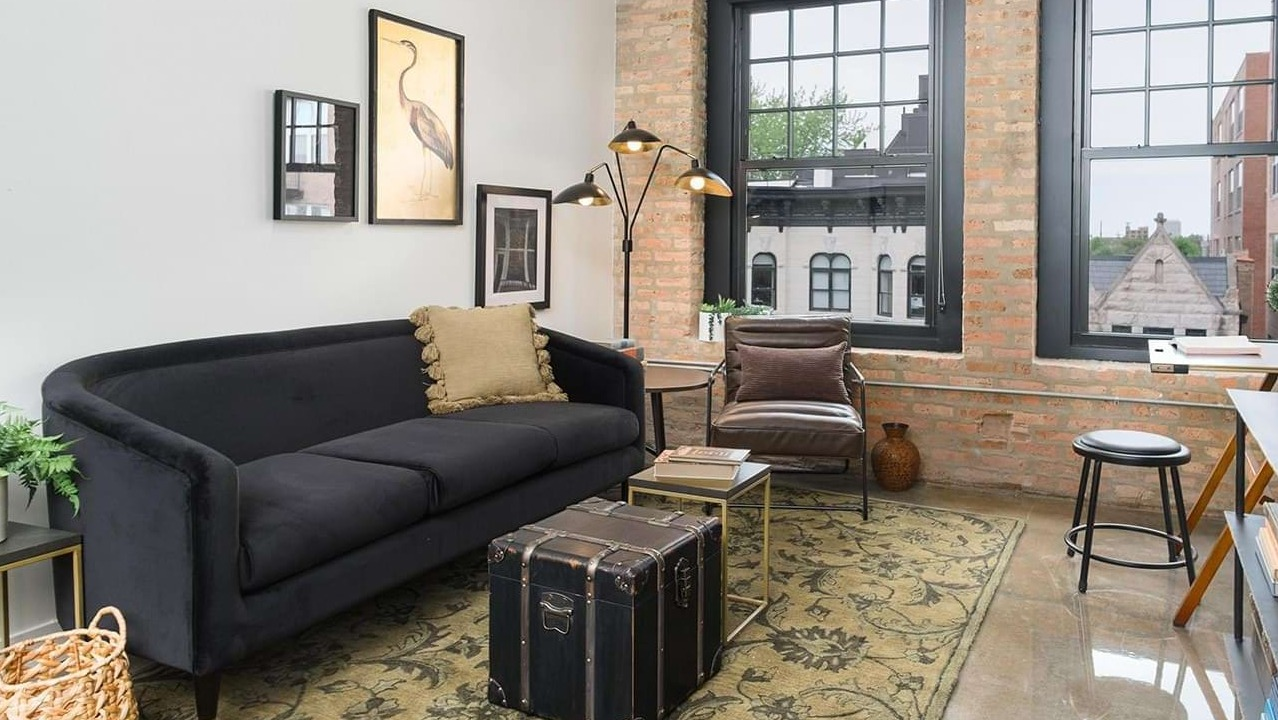 Industrial-style living room with exposed brick, a black sofa, and unique decor elements, offering a cozy ambiance at The Duncan in Chicago