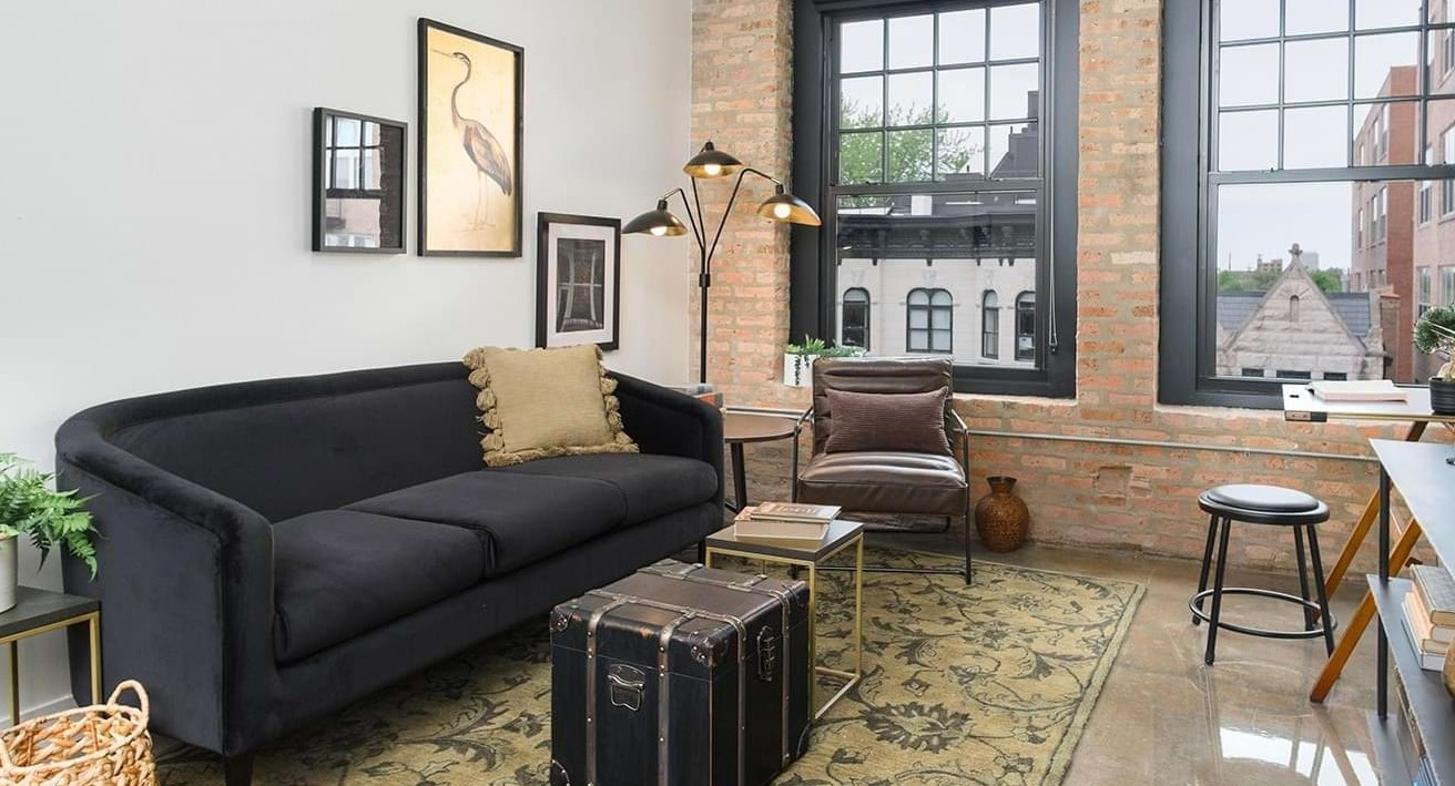 Industrial-style living room with exposed brick, a black sofa, and unique decor elements, offering a cozy ambiance at The Duncan in Chicago