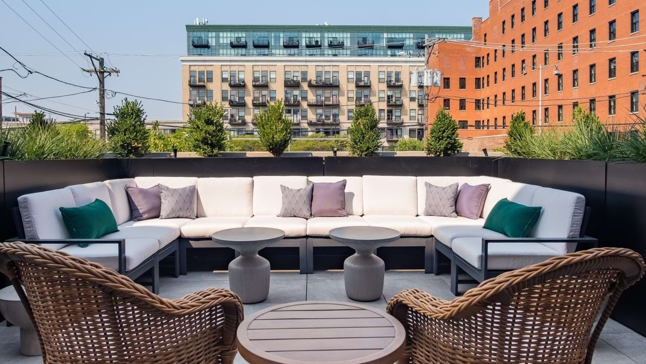Charming outdoor lounge area with comfortable upholstered seating and lush greenery, providing a tranquil escape at The Duncan in Chicago