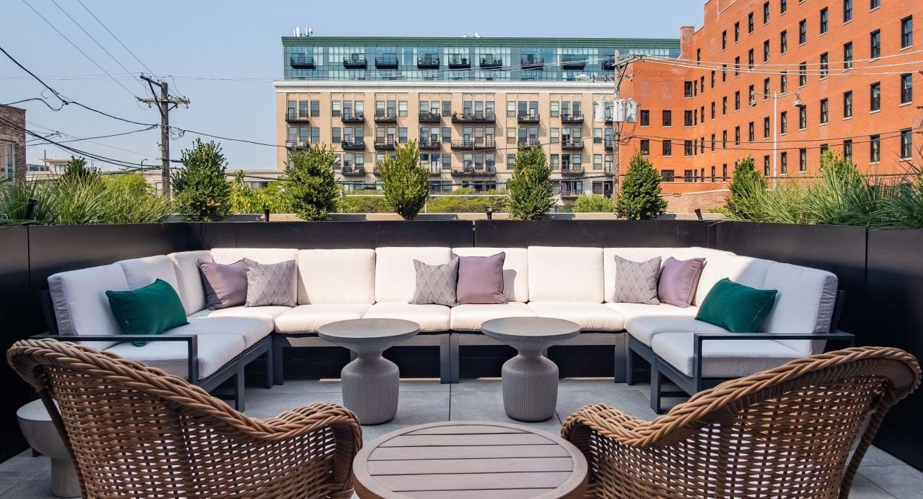 Charming outdoor lounge area with comfortable upholstered seating and lush greenery, providing a tranquil escape at The Duncan in Chicago