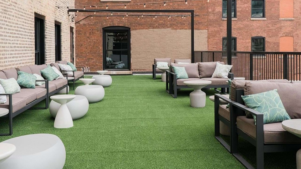 Spacious rooftop patio with comfortable outdoor sofas, string lights, and artificial turf, perfect for relaxing at The Duncan in Chicago