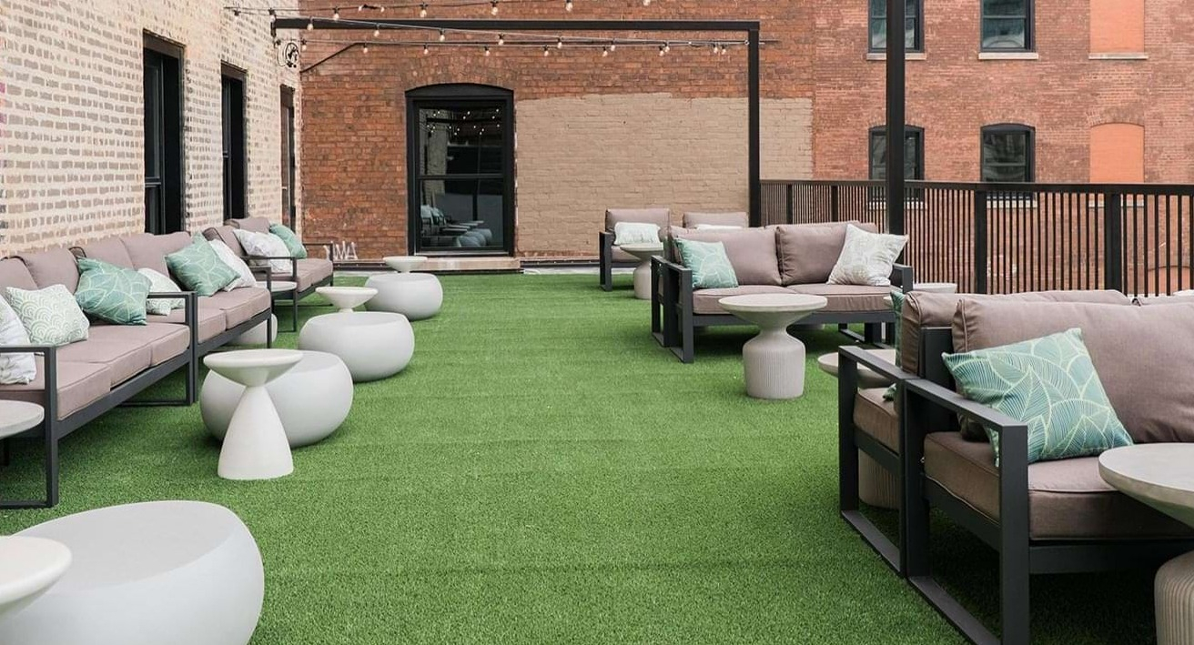 Spacious rooftop patio with comfortable outdoor sofas, string lights, and artificial turf, perfect for relaxing at The Duncan in Chicago