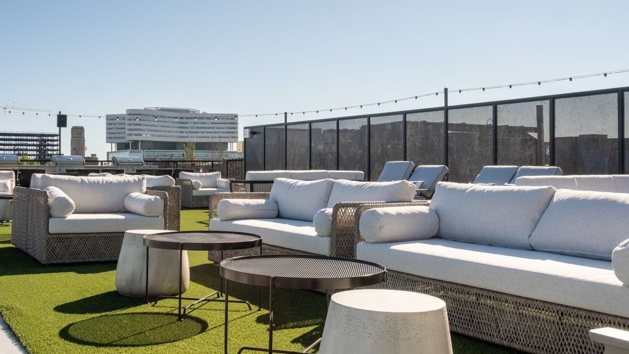 Sunny rooftop deck with modern white outdoor sofas, sun loungers, and city views, ideal for relaxation at The Duncan in Chicago