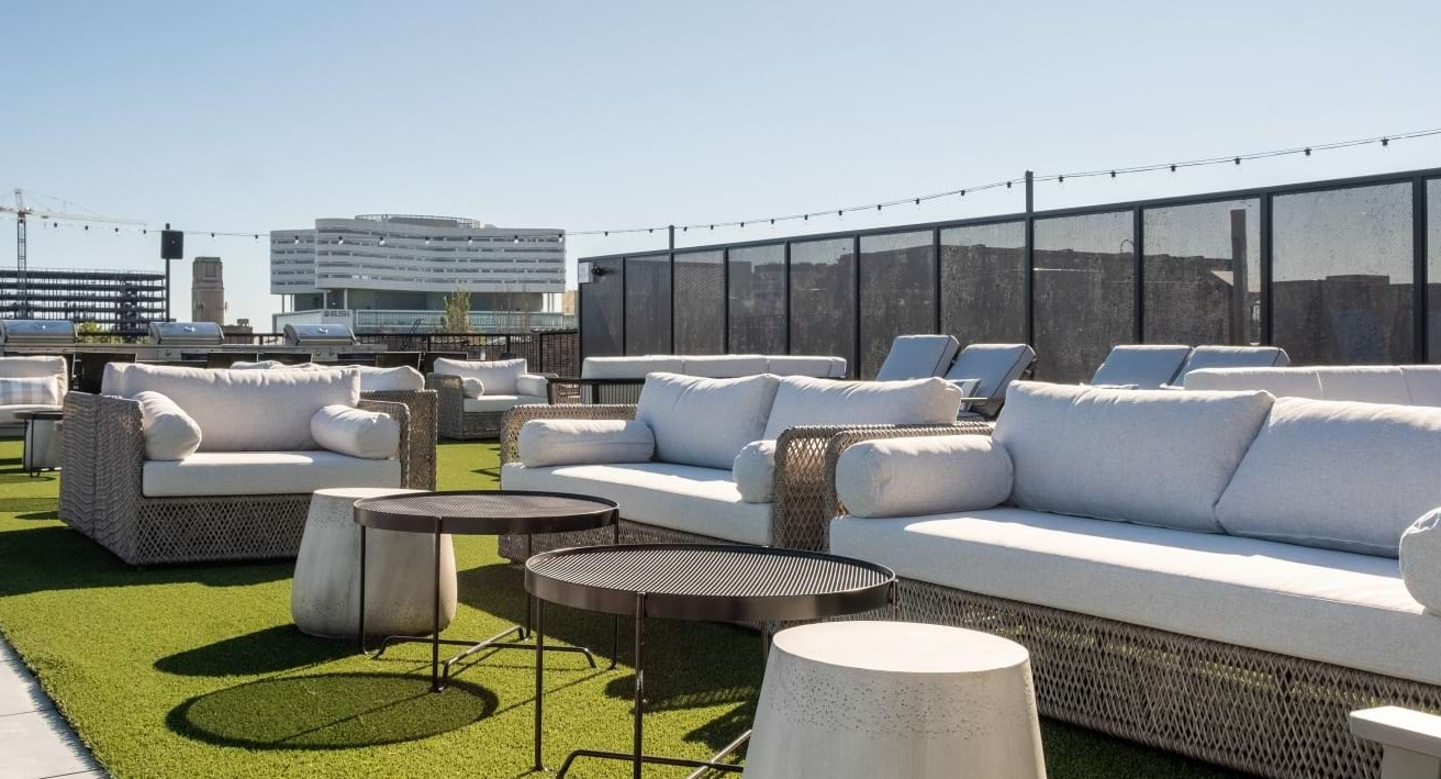 Sunny rooftop deck with modern white outdoor sofas, sun loungers, and city views, ideal for relaxation at The Duncan in Chicago