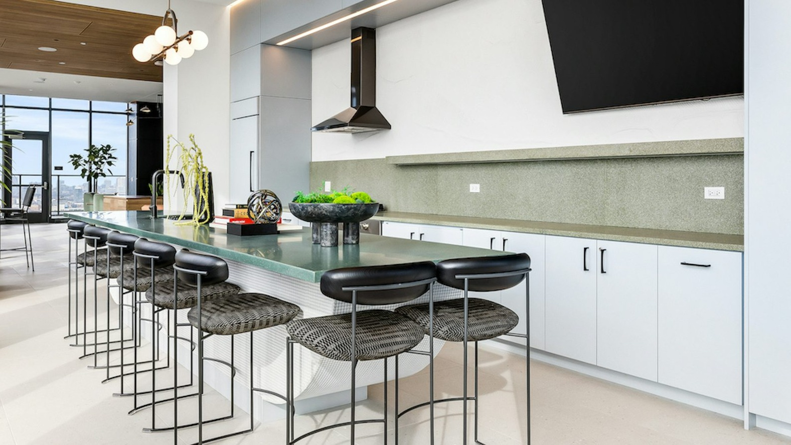 Amenity chef's kitchen at The Dylan in Chicago featuring a long, light green communal bar with seating and modern lighting