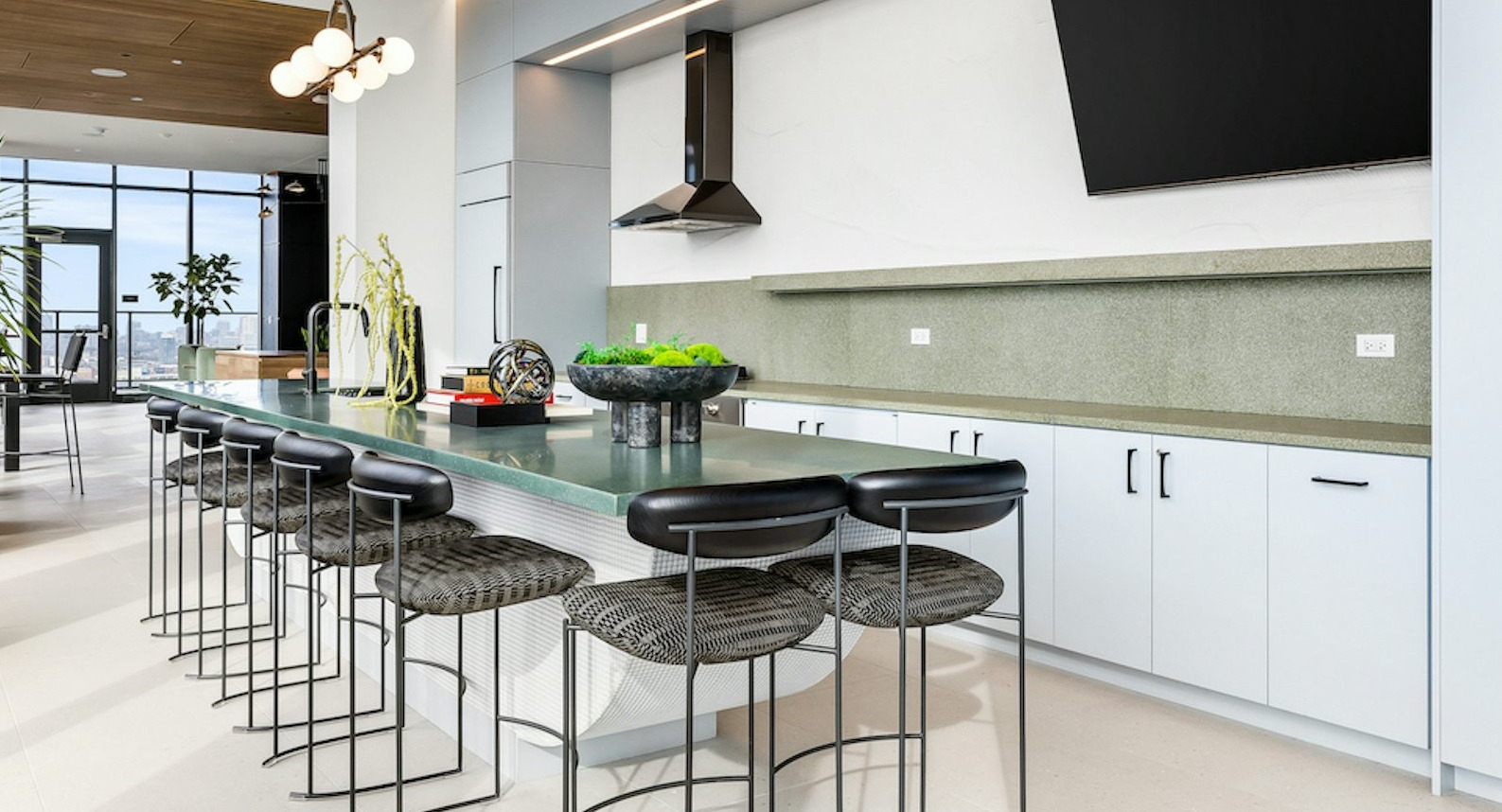 Amenity chef's kitchen at The Dylan in Chicago featuring a long, light green communal bar with seating and modern lighting