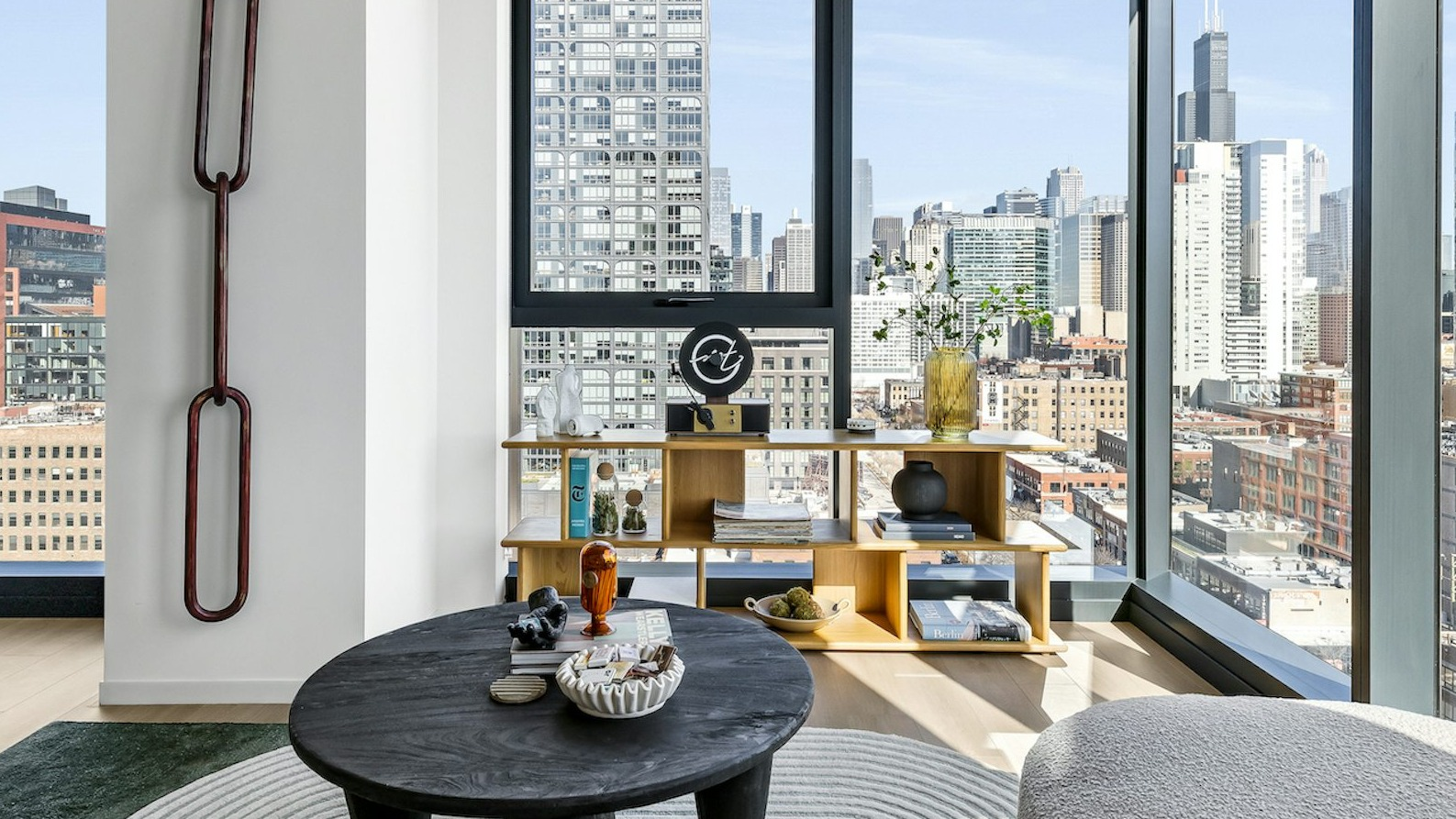 Spacious apartment living room with floor-to-ceiling windows offering breathtaking city skyline views, featuring stylish decor and a comfortable sofa at The Dylan in Chicago