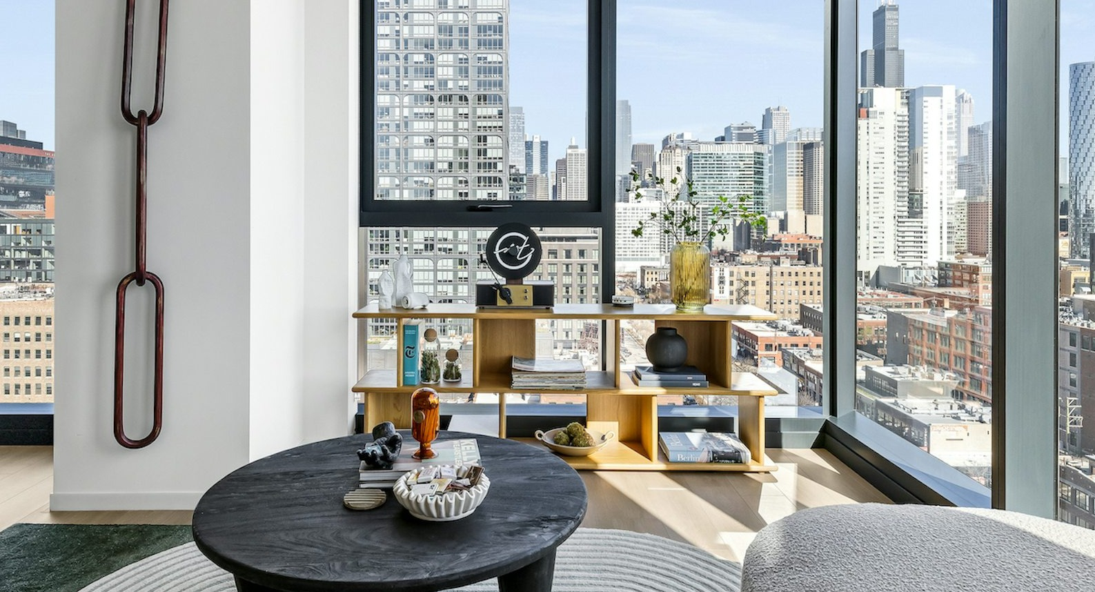 Spacious apartment living room with floor-to-ceiling windows offering breathtaking city skyline views, featuring stylish decor and a comfortable sofa at The Dylan in Chicago