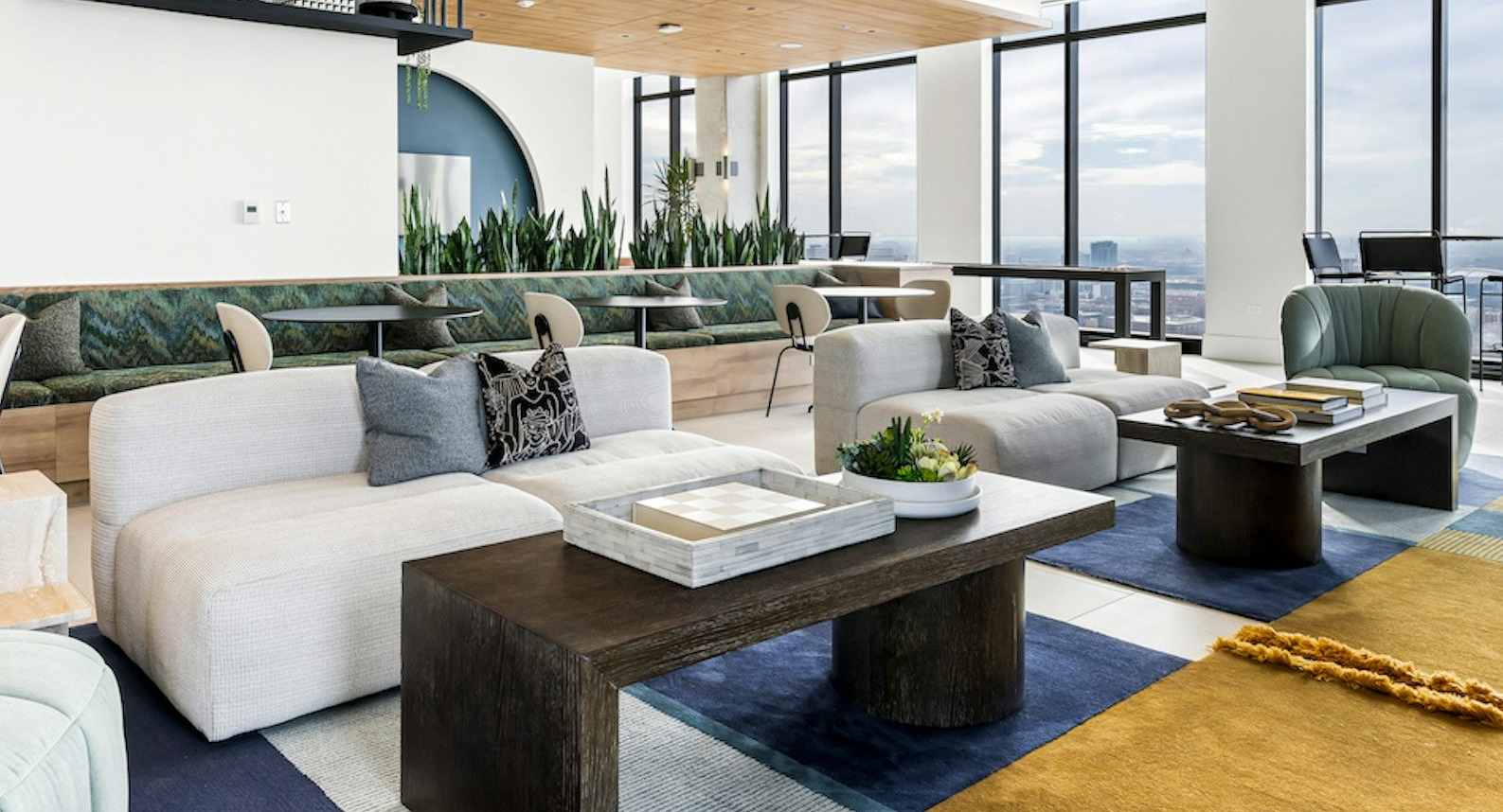 Elegant resident lounge area with diverse seating arrangements, stylish decor, and panoramic city views from large windows at The Dylan in Chicago