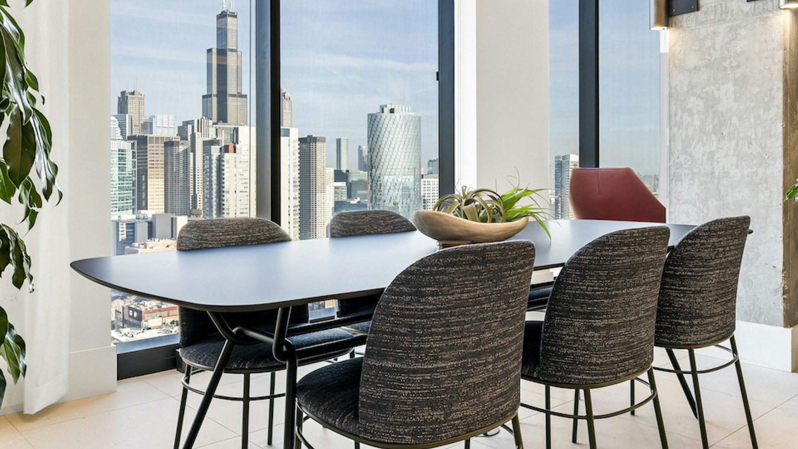 High-rise dining area at The Dylan in Chicago with a large table, contemporary chairs, and a stunning city view