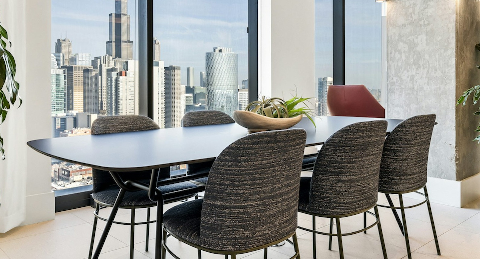 High-rise dining area at The Dylan in Chicago with a large table, contemporary chairs, and a stunning city view