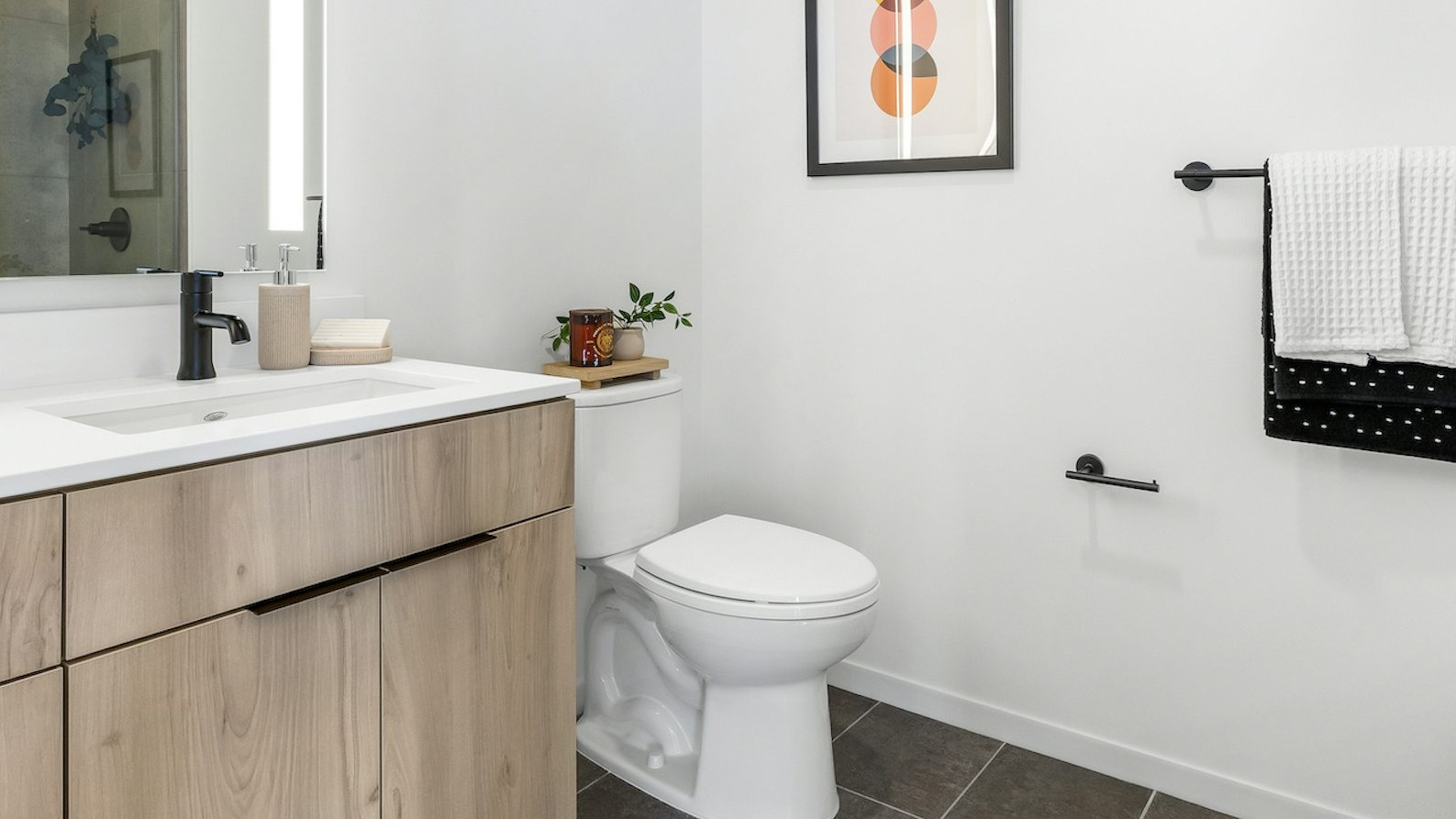 Luxury apartment bathroom at The Dylan in Chicago with a light wood vanity, modern sink, and dark tiled floor