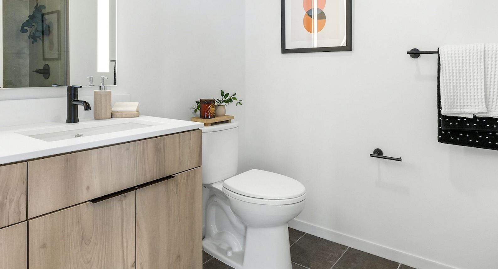 Luxury apartment bathroom at The Dylan in Chicago with a light wood vanity, modern sink, and dark tiled floor