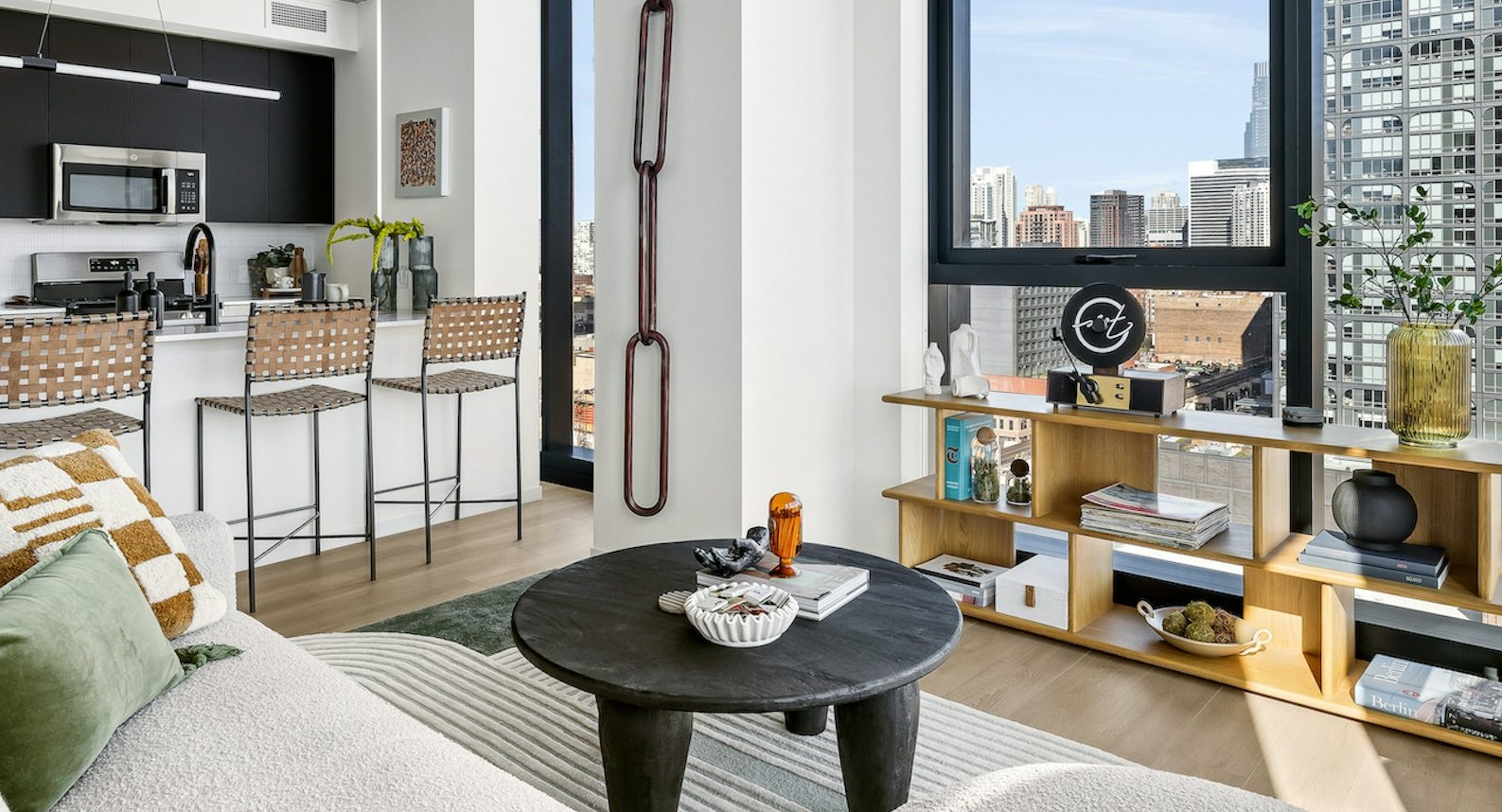 Chic apartment living room with a comfortable sofa, unique coffee table, and an integrated kitchen with bar seating at The Dylan in Chicago