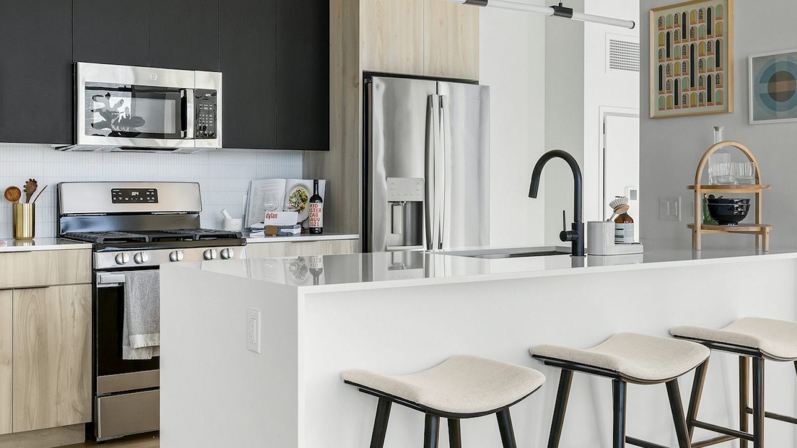 Sleek modern kitchen with two-toned cabinetry, stainless steel appliances, a large island with bar stools, and artistic decor at The Dylan in Chicago