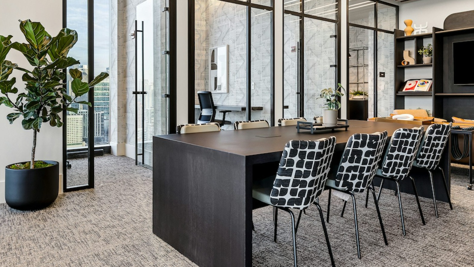 Modern co-working space at The Dylan in Chicago featuring a glass-enclosed conference room and contemporary seating