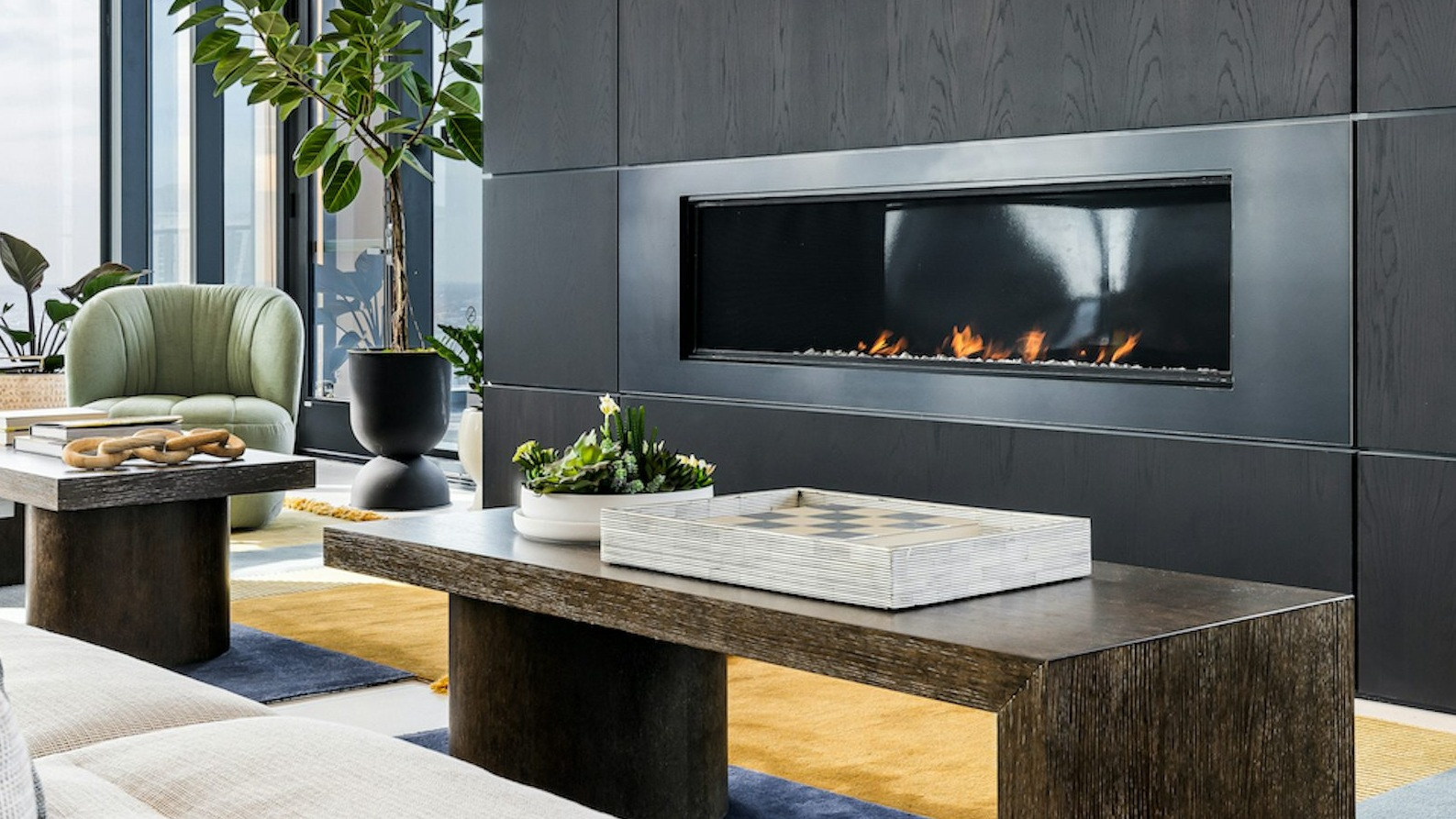 Elegant resident lounge with modern furniture, a cozy fireplace, and large windows providing panoramic city views at The Dylan in Chicago