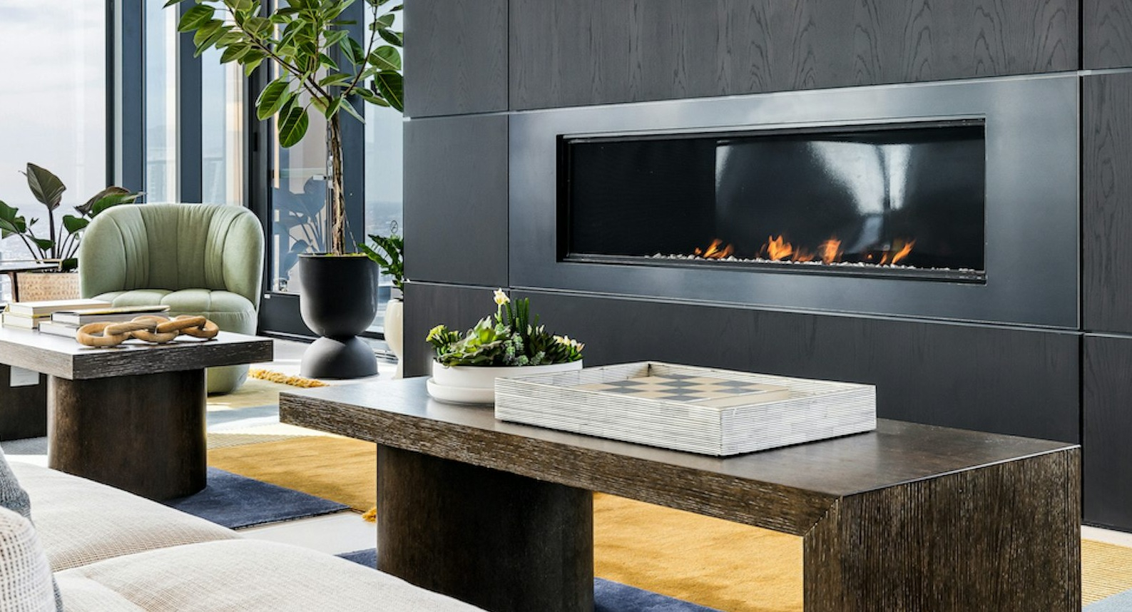 Elegant resident lounge with modern furniture, a cozy fireplace, and large windows providing panoramic city views at The Dylan in Chicago