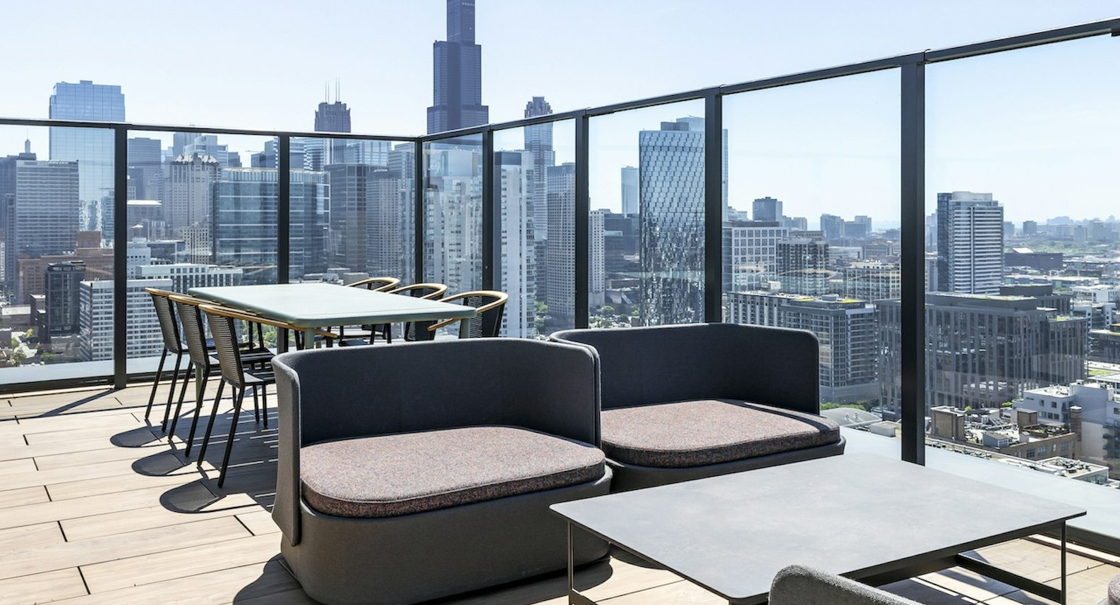 Expansive rooftop lounge area with modern outdoor seating, dining tables, and spectacular panoramic views of the Chicago skyline at The Dylan