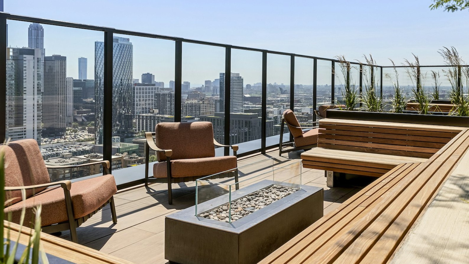 Inviting rooftop terrace with comfortable seating, built-in benches, a modern fire pit, and stunning city skyline views at The Dylan in Chicago