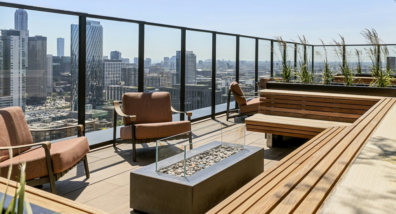 Inviting rooftop terrace with comfortable seating, built-in benches, a modern fire pit, and stunning city skyline views at The Dylan in Chicago