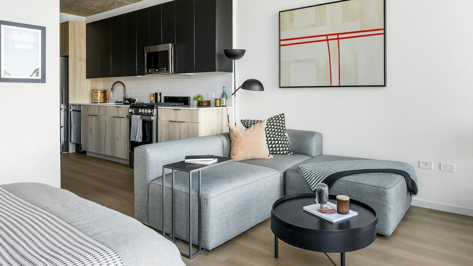 Modern studio apartment featuring a well-appointed kitchen, comfortable sectional sofa, and artistic decor at The Dylan in Chicago