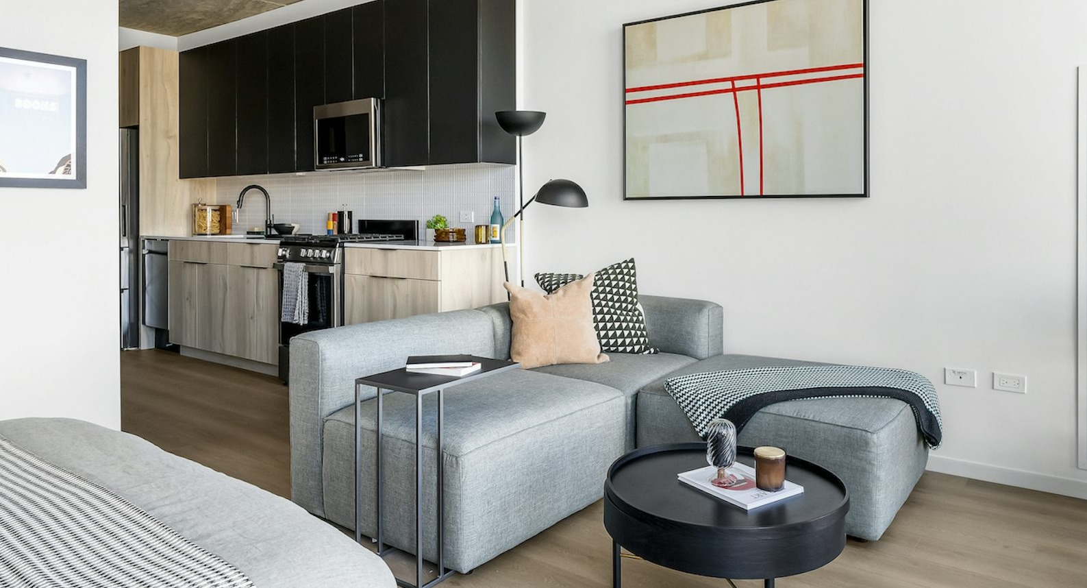 Modern studio apartment featuring a well-appointed kitchen, comfortable sectional sofa, and artistic decor at The Dylan in Chicago
