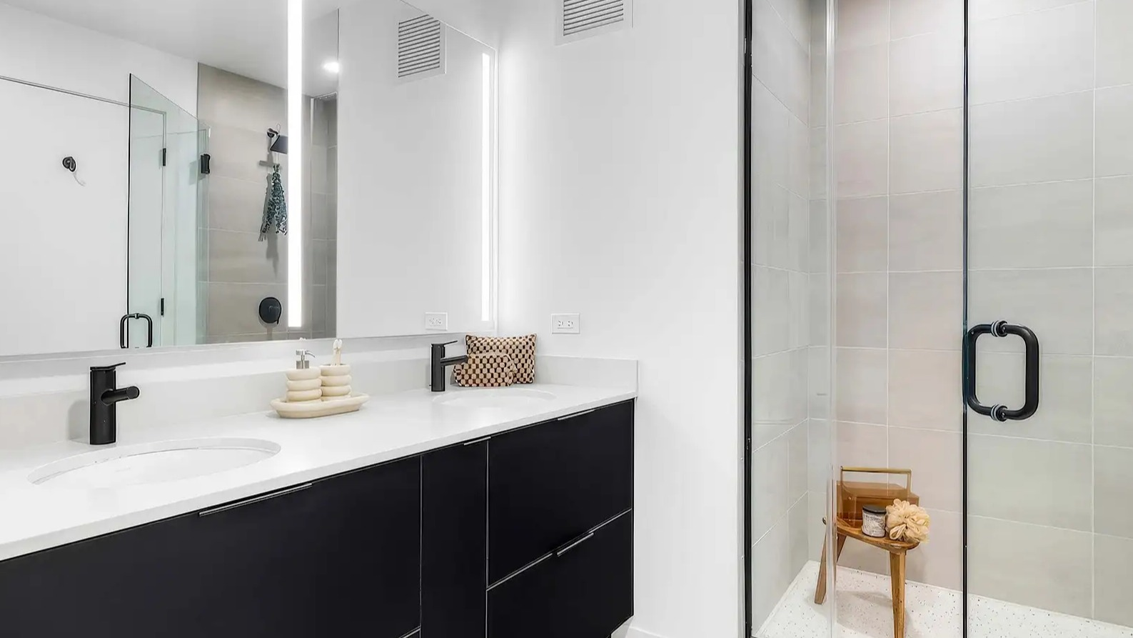 Luxurious apartment bathroom at The Elizabeth Chicago, featuring a dual vanity, large illuminated mirror, and a spacious walk-in shower