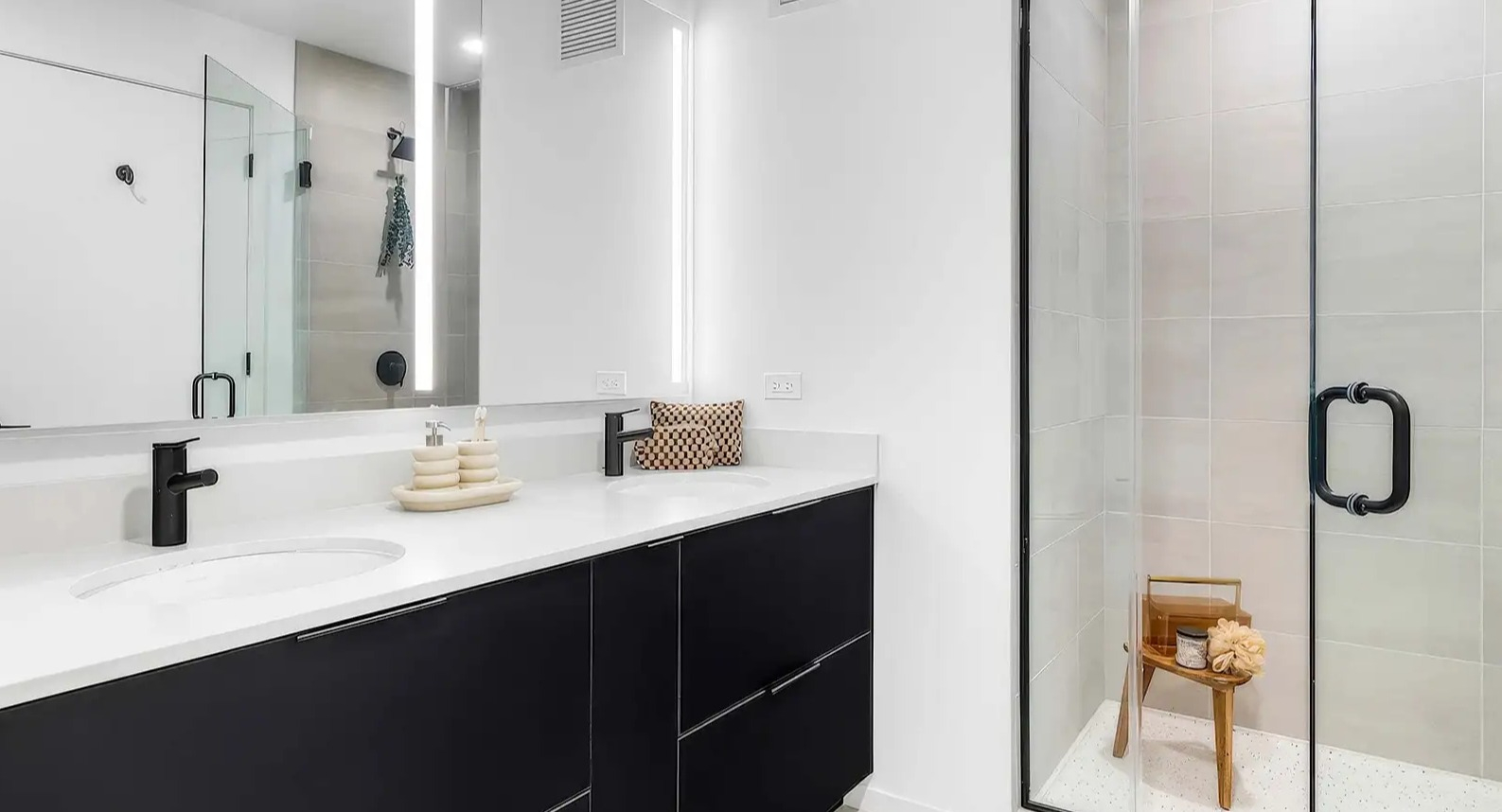 Luxurious apartment bathroom at The Elizabeth Chicago, featuring a dual vanity, large illuminated mirror, and a spacious walk-in shower
