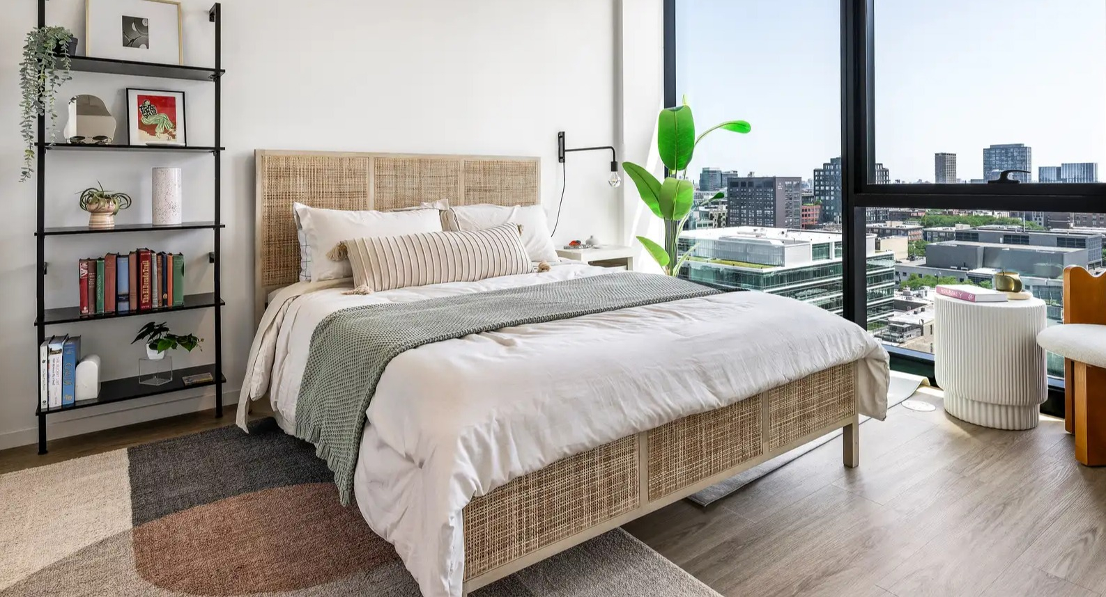 Modern apartment bedroom at The Elizabeth Chicago, featuring a comfortable bed, stylish shelving, and large windows with city views