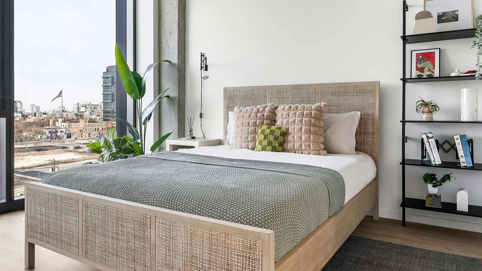 Bright apartment bedroom at The Elizabeth Chicago, featuring a natural wood bed frame, stylish decor, and expansive urban views
