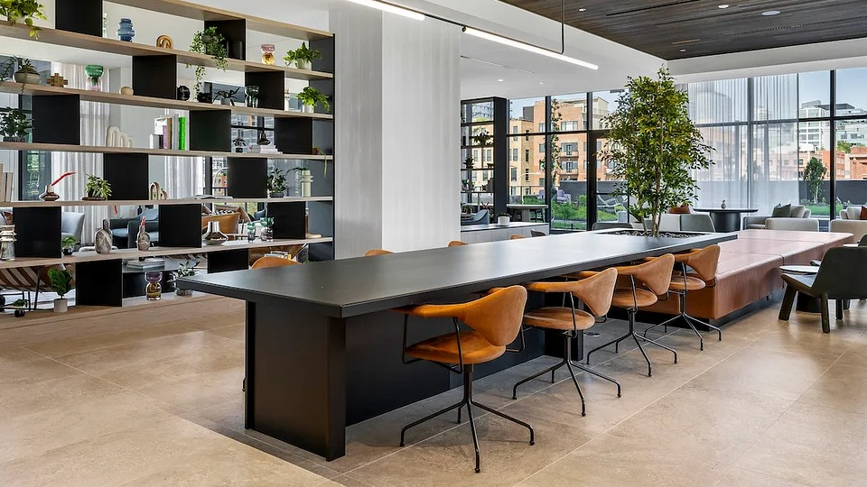 Stylish co-working space at The Elizabeth Chicago, featuring a long communal table, individual desks, and modern shelving