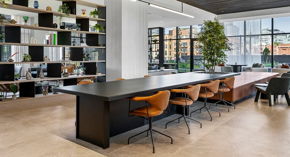 Stylish co-working space at The Elizabeth Chicago, featuring a long communal table, individual desks, and modern shelving
