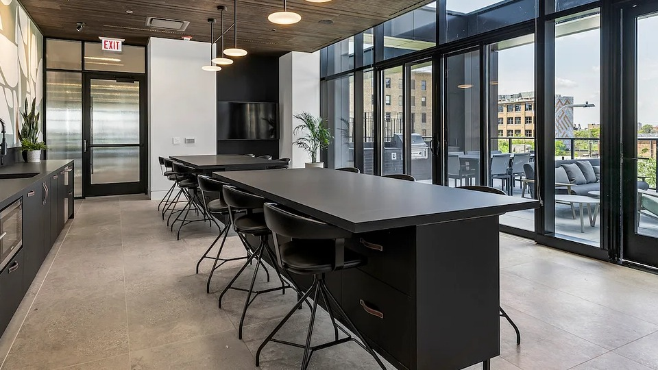 Modern community kitchen at The Elizabeth Chicago, featuring dark cabinetry, a long island, and ample space for gatherings