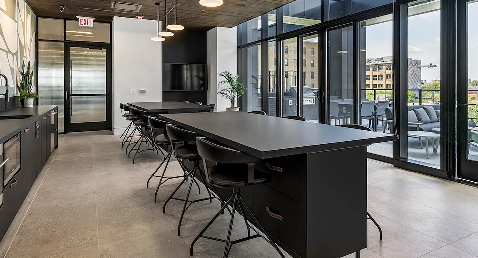 Modern community kitchen at The Elizabeth Chicago, featuring dark cabinetry, a long island, and ample space for gatherings