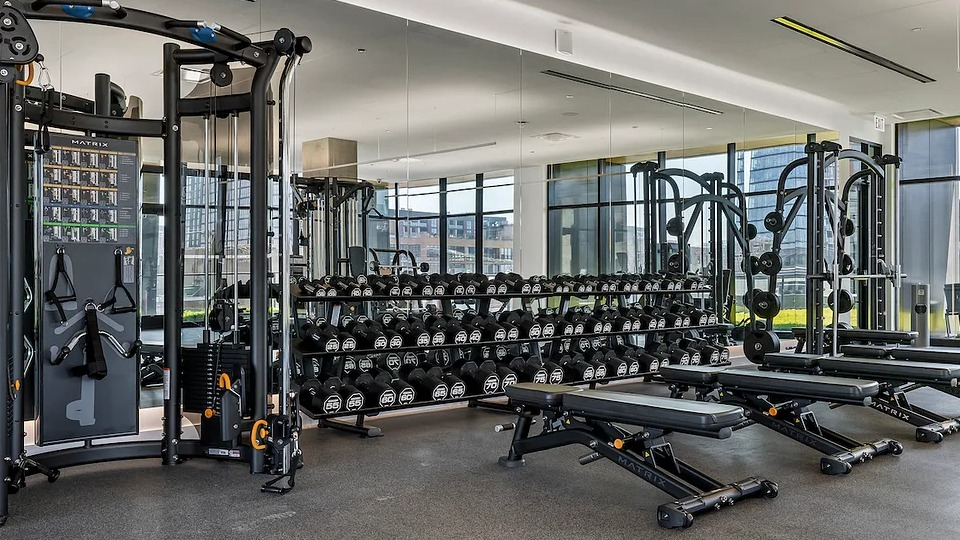Fully equipped gym at The Elizabeth Chicago, featuring free weights, benches, and strength training equipment with mirrored walls