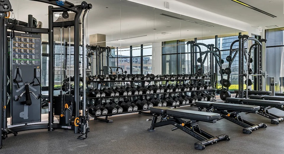 Fully equipped gym at The Elizabeth Chicago, featuring free weights, benches, and strength training equipment with mirrored walls