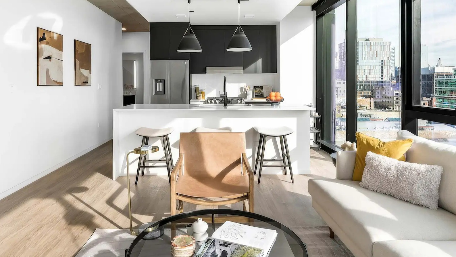 Modern living room and compact kitchenette at The Elizabeth Chicago, featuring a comfortable sofa and abundant natural light with city views