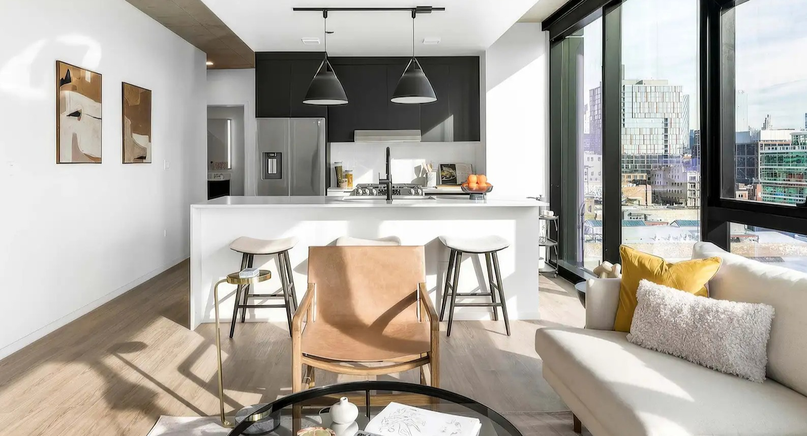 Modern living room and compact kitchenette at The Elizabeth Chicago, featuring a comfortable sofa and abundant natural light with city views
