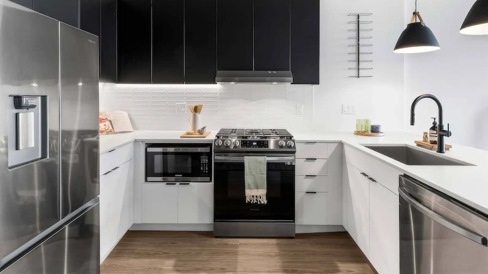 Sleek modern kitchen at The Elizabeth Chicago, featuring contrasting black and white cabinetry, stainless steel appliances, and pendant lighting