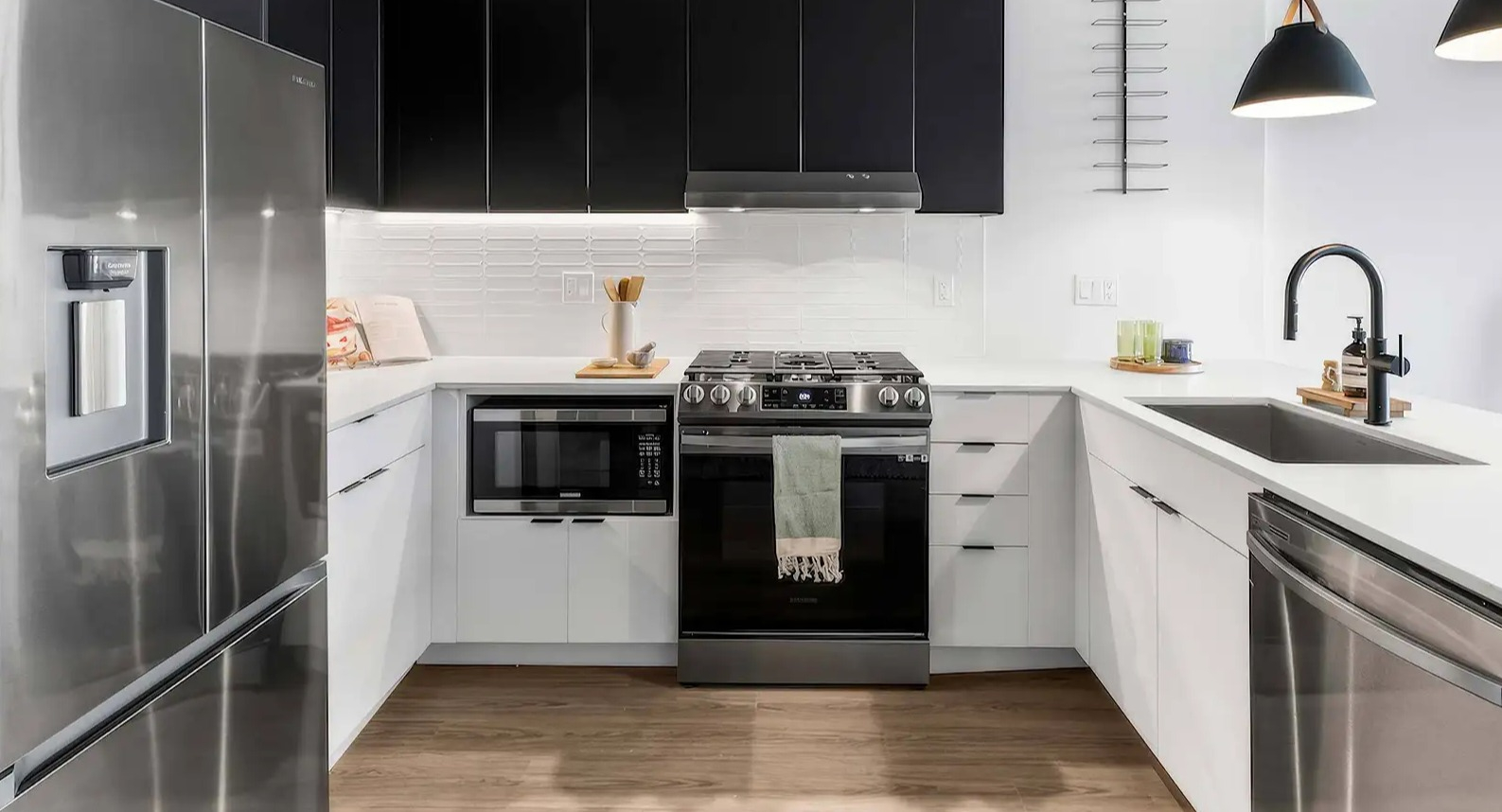 Sleek modern kitchen at The Elizabeth Chicago, featuring contrasting black and white cabinetry, stainless steel appliances, and pendant lighting